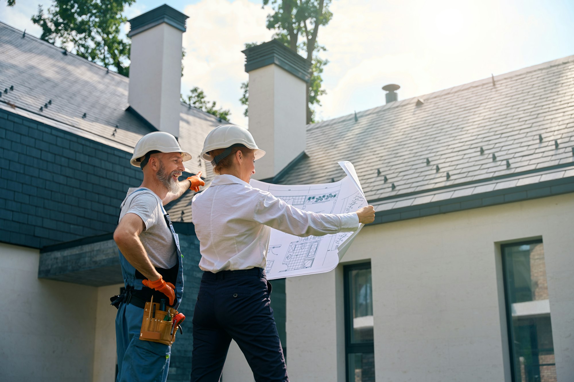 Builder and site supervisor using blueprints during building facade inspection